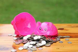 A broken pink piggy bank is isolated on a wooden floor background. photo