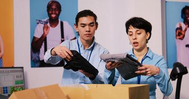 diverso Tienda gerentes preparando paquetes para envío, poniendo elegante ropa en caja de cartón cajas en moderno boutique. empleados trabajando a clientela pedidos, que se discute entrega detalles en compras centro comercial foto