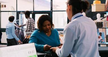 African american woman paying for fashionable clothes at counter desk, putting credit card on pos terminal in modern boutique, Stylish customer buying trendy merchandise in shopping centre photo