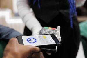 camarero participación pos terminal aceptar sin efectivo transacción desde cliente en restaurante o hotel. cliente pago con teléfono, haciendo móvil pago, utilizando nfc pago aplicación, cerca arriba foto