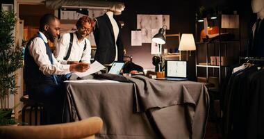 Team of designers choosing material to create modern fashion items with tailoring equipment. Business partners tailors working with fabric and tools, designing handmade clothes. photo