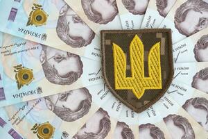 Ukrainian military symbol and hryvnia bills. Payments to soldiers of the Ukrainian army, salaries to the military photo