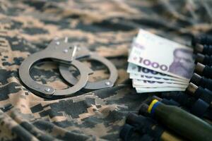 Ukrainian army machine gun belt shells and handcuffs on military uniform. Concept of bribery and war crimes photo