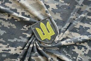 Symbol of Ukrainian army on the camouflage uniform of a Ukrainian soldier. The concept of war in Ukraine, patriotism and protecting your country from occupiers photo