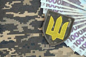 Ukrainian army symbol and bunch of hryvnia bills on military uniform. Payments to soldiers of the Ukrainian army, salaries to the military photo