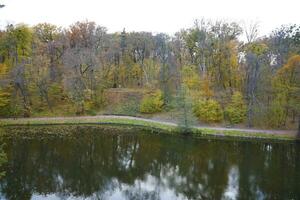 Beautiful Nature Autumn landscape with lake. Scenery view on autumn city park with golden yellow foliage in cloudy day photo