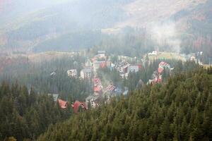 Morning view of residental area and houses around the Dragobrat mountain peaks in Carpathian mountains, Ukraine. Cloudy and foggy landscape around Drahobrat Peaks photo