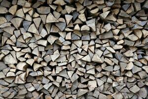 Firewood stacked near the wooden wall of old hut. Many chopped logs of firewood photo