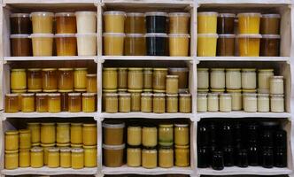 Jars of different honey varieties stocked on a shelf. Lavender, linden and mixed honey photo
