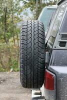 rueda de cerca en un campo paisaje con un barro la carretera. fuera del camino 4x4 suv automóvil con ditrito cuerpo después conducir en lodoso la carretera foto