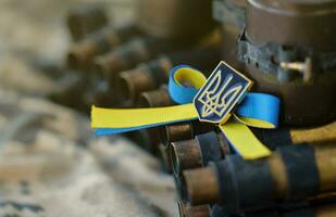 Ukrainian symbol on machine gun belt lies on ukrainian pixeled military camouflage photo