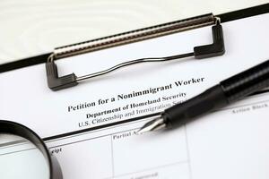 I-129 Petition for a nonimmigrant worker blank form on A4 tablet lies on office table with pen and magnifying glass photo