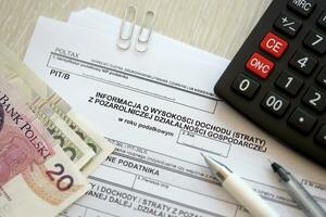 Information on amount of income or loss from non-agricultural economic activity, PIT-B form on accountant table with pen and polish zloty money bills photo