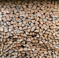 Firewood stacked near the wooden wall of old hut. Many chopped logs of firewood photo