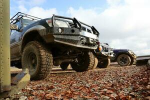 Automobile in a countryside landscape with a mud road. Off-road 4x4 suv automobile with ditry body after drive in muddy road photo