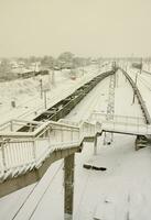 A long train of freight cars is moving along the railroad track. Railway landscape in winter after snowfall photo