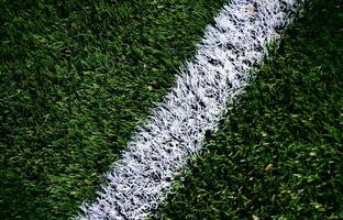 White stripe on a bright green artificial grass soccer field photo