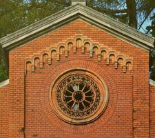 Texture front part of an ancient brick crypt with a round patterned carved window in the cemetery photo