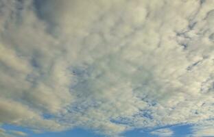 A blue cloudy sky with many small clouds blocking the sun photo