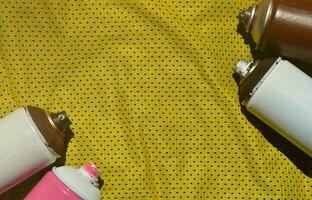 varios rociadores de pintura en aerosol usados yacen en la camiseta deportiva de un jugador de baloncesto hecha de tela de poliéster. el concepto de arte callejero juvenil, deportes activos y estilo de vida agitado foto