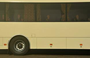 Photo of the hull of a large and long yellow bus with free space for advertising. Close-up side view of a passenger vehicle for transportation and tourism