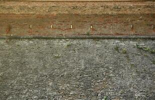 Very old brick stone wall of castle or fortress of 18th century. Full frame wall with obsolete dirty and cracked bricks photo