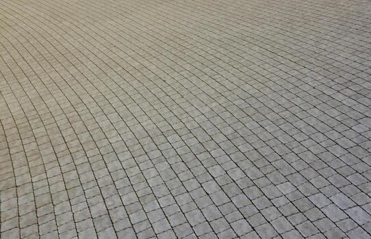 Gray color paving slabs in the pedestrian street sidewalk. Rough cobblestone pattern with many square shaped stones photo