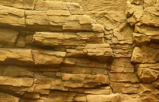 fondo de piedra de roca natural gruesa y clara. superficie frontal rugosa del acantilado minero. gran pila de piedra caliza como telón de fondo. textura de bloque de granito dañado grunge pesado foto