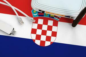 Croatia flag depicted on table with internet rj45 cable, wireless usb wifi adapter and router. Internet connection concept photo