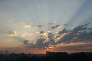 Beautiful sunrise with warm orange sunlight and beams through blue sky photo