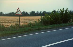 Empty asphalt road and floral field of different grass and flowers in evening time photo