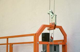 Hoist supply and safety lock as part of suspended wire rope platform for facade works on high multistorey buildings. Hoist for elevation, raising or lifting cradle photo