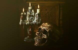 Old battered skull lies with an antique wooden candlestick photo
