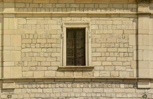 Very old window in brick stone wall of castle or fortress of 18th century. Full frame wall with window photo