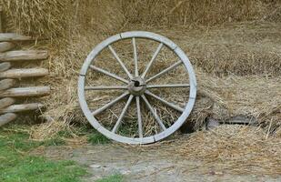 Place with stacks of hay cubes and rustic wooden wheels of old cart photo