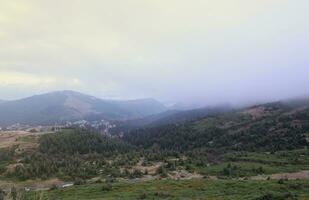 Morning view from the Dragobrat mountain peaks in Carpathian mountains, Ukraine. Cloudy and foggy landscape around Drahobrat Peaks photo