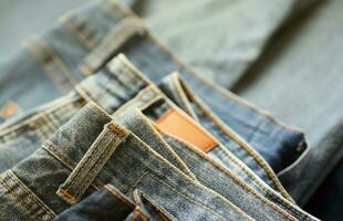 Many jeans in stack in wardrobe room. Row of pants denim jeans in closet. Concept of buy, sell, shopping and fashionable clothes photo