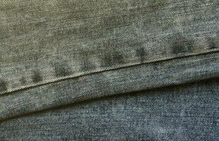 Detailed abstract texture of dark blue denim cloth. Background image of old used denim trousers fabric photo