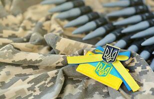 Ukrainian symbol and a machine gun belt on the camouflage uniform of a Ukrainian soldier. The Concept of war in Ukraine, patriotism and protecting your country from occupiers photo