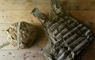 A military helmet of a Ukrainian soldier with a heavy bulletproof vest on wooden table in checkpoint dugout photo