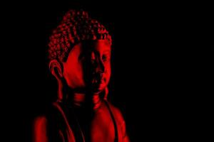 Buda purnima y vesak día concepto, rojo Buda estatua con bajo llave ligero en contra profundo negro antecedentes foto