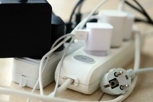 Overloaded power boards. Power strips with different electrical plugs on white floor photo