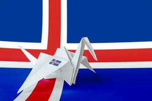 Iceland flag depicted on paper origami crane wing. Handmade arts concept photo