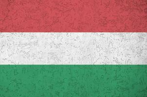 Hungary flag depicted in bright paint colors on old relief plastering wall. Textured banner on rough background photo