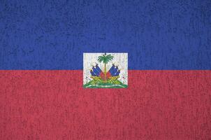 Haiti flag depicted in bright paint colors on old relief plastering wall. Textured banner on rough background photo