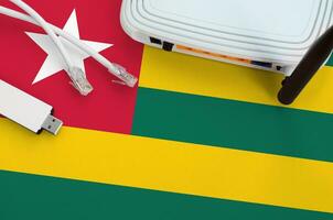 Togo flag depicted on table with internet rj45 cable, wireless usb wifi adapter and router. Internet connection concept photo