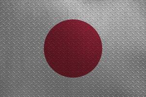 Japan flag depicted in paint colors on old brushed metal plate or wall closeup. Textured banner on rough background photo