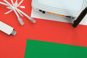 Oman flag depicted on table with internet rj45 cable, wireless usb wifi adapter and router. Internet connection concept photo