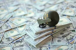 Grenade with a check against the background of huge amount of american dollar bills photo