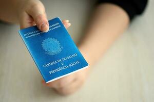 Woman boss gives a brazilian work card and social security blue book to us in employment office photo